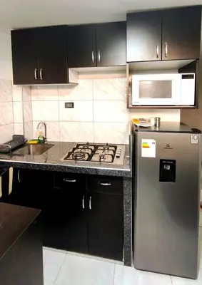 a kitchen with black cabinets and a stainless steel refrigerator at Departamento centro in Andahuaylas