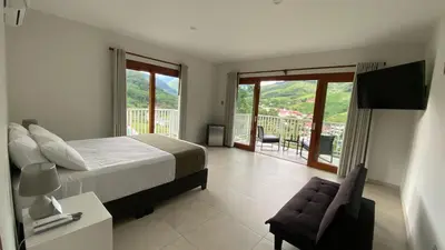 a bedroom with a bed and a chair and a balcony at Göttlich Boutique Hotel in Pozuzo