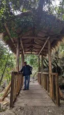 a man walking across a wooden bridge at EcoLodge Mayu Camping in Tanca