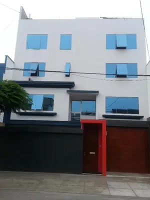 a white building with a red door in front of it at Hermoso Departamento en Pueblo Libre in Lima