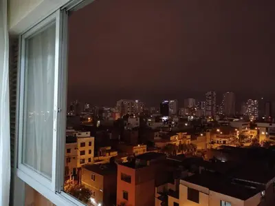 a view of a city at night from a window at Apartamento cómodo, como tu hogar in Lima