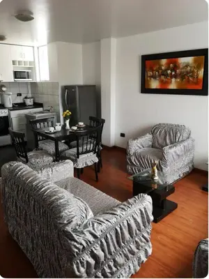 a living room with couches and a table and a kitchen at Edificio La Católica in Lima