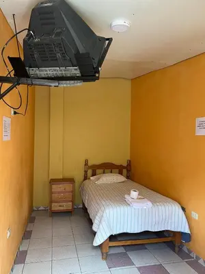 a bedroom with a bed and a tv hanging from the ceiling at Hospedaje El Centro in Ayacucho