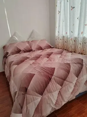 a bed with a pink comforter in a bedroom at Apartamento de Kelita in Ayacucho