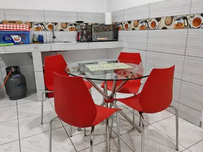 a glass table with red chairs in a kitchen at Apartamento de Kelita in Ayacucho