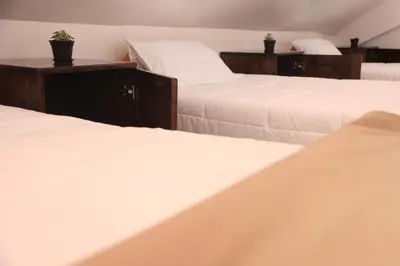 three beds in a room with white sheets at Anata Hotel in Cusco