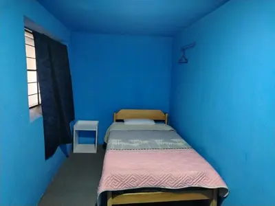 a blue bedroom with a bed and a window at CASa HOSPEDAJE RODRÍGUEZ in Urubamba