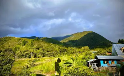 a house on a hill with mountains in the background at Colina Haus, cabaña familiar Oxa in Oxapampa