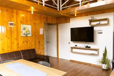 a living room with a couch and a flat screen tv at Colina Haus, cabaña familiar Oxa in Oxapampa