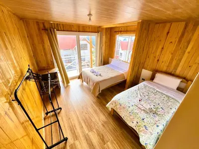 a room with two beds in a wooden room at Colina Haus, cabaña familiar Oxa in Oxapampa