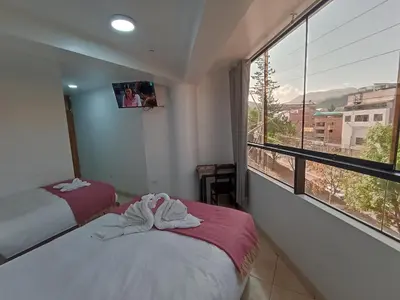 two beds in a room with a large window at Templo Home in Cusco
