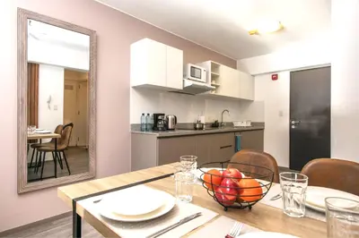 a kitchen and dining room with a table and a mirror at Cozy modern heart of city in Cusco