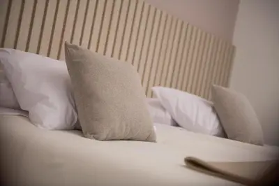 a white bed with white pillows on it at Cozy modern heart of city in Cusco
