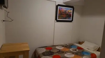 a small room with a bed with a picture on the wall at Samay Ñawi Wasi in Cusco