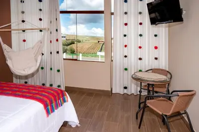 a bedroom with a bed and a table and a window at Vive Chinchero in Ayarmaca