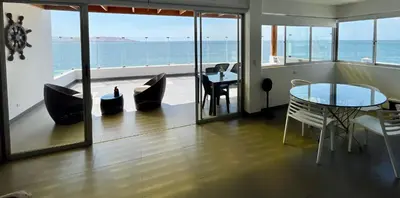 a living room with a table and chairs and the ocean at Suite 1ra Fila Vista Bahía Paracas - Sotavento 601 T3 in Paracas