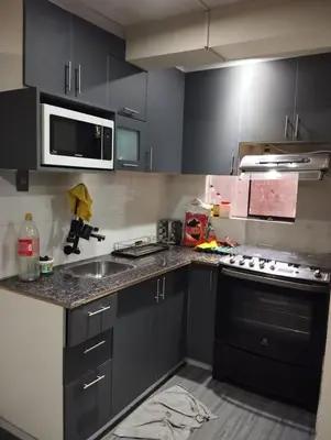 a kitchen with black cabinets and a sink and a microwave at Departamento Duplex Aeropuerto y plaza cerca de ti! in Lima
