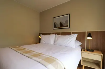 a bedroom with a large white bed and a lamp at Treehouse by Wynwood house in Lima