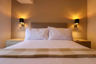 a bedroom with a bed with white pillows and lights at Studio 4 by Wynwood House in Lima