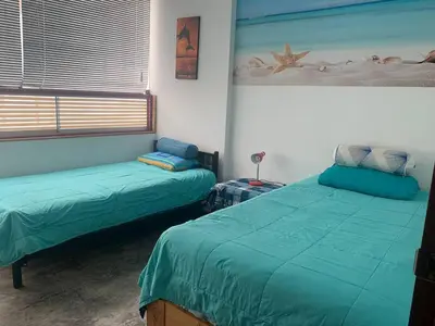 a bedroom with two beds with green sheets and a window at Ali Home in Punta Negra