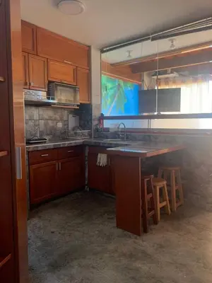 a kitchen with wooden cabinets and a kitchen island with stools at Ali Home in Punta Negra