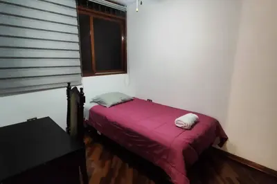 a bedroom with a bed with a purple blanket and a window at Casa de 4 pisos cerca a embajada de USA y centros comerciales in Lima