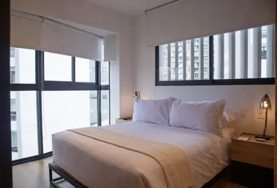 a bedroom with a large white bed with two windows at Pendragon by Wynwood House in Lima