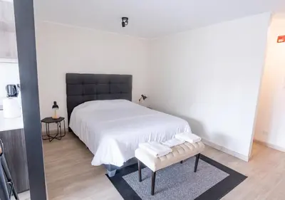 a bedroom with a white bed with a black headboard at Maravilla en barranco BR1 in Lima