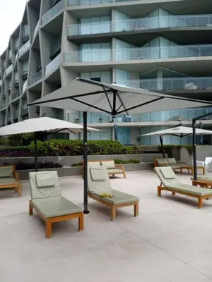 a group of chairs and umbrellas in front of a building at Departamento en PLAYA San Bartolo in San Bartolo