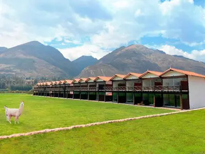 a building with a sheep in a field with mountains at RUSTICA HOTELES CUSCO Urubamba in Pachar