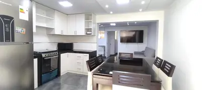 a kitchen with white cabinets and a table and chairs at El Polo Surco in Lima