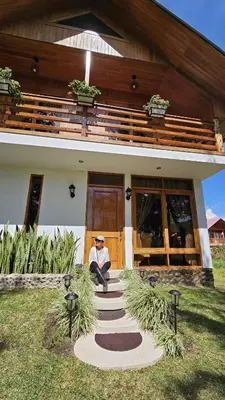 a man sitting on the steps of a house at Posada de la Sirga Oxapampa De 8 a 10 personas in Oxapampa