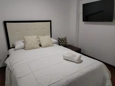 a bedroom with a white bed with a flat screen tv at El Libertador Apartment Miraflores in Lima
