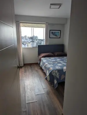 a bedroom with a bed and a large window at Guernica Apartments in Lima