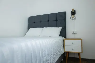 a bed with a black headboard next to a night stand at Modern Duplex by the sea Miraflores in Lima