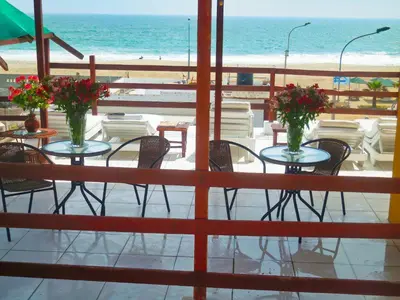 a patio with tables and chairs and the beach at Hostal Ocean Pacifico in Punta Negra