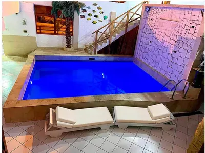 a large swimming pool with two chairs and a staircase at Hostal Ocean Pacifico in Punta Negra