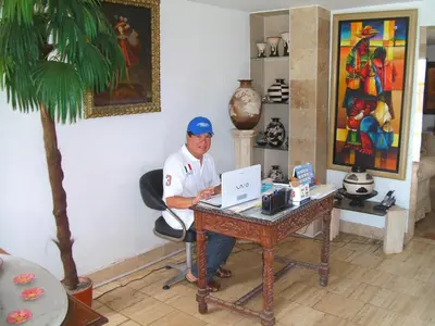 a man sitting at a desk with a laptop at Hostal Ocean Pacifico in Punta Negra