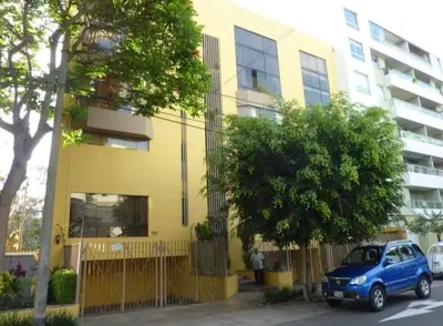 a blue car parked in front of a yellow building at Departamento jacuzzi Miraflores in Lima