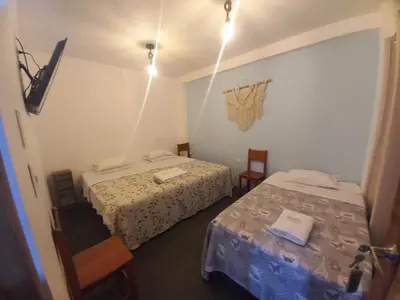 a small room with two beds and two chairs at Hospedaje Velilu in Ica