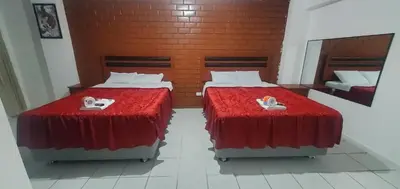 two beds in a room with red sheets and shoes at Hospedaje El Paraiso in Santa Eulalia