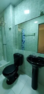 a bathroom with a black toilet and a sink at Hospedaje El Paraiso in Santa Eulalia