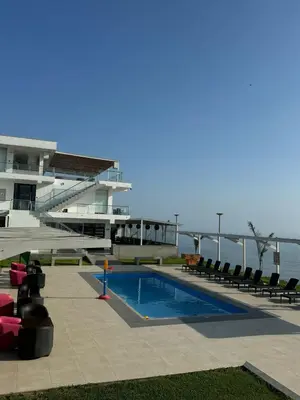 a swimming pool in front of a building with the ocean at Vista a Mar in Huaral