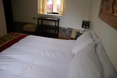 a white bed in a bedroom with a window at Hotel Samanapaq in Ollantaytambo
