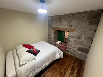 a bedroom with a bed and a stone wall at Acogedor Departamento en Barrio Resbalosa, a 5 Min de la Plaza de Cusco in Cusco