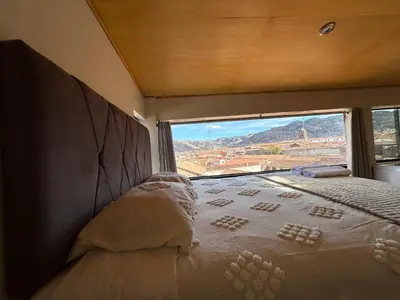 a bed in a room with a large window at Duplex panorámico in Cusco