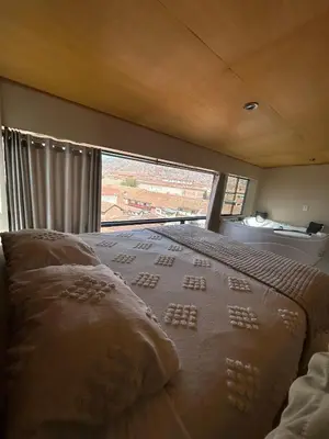 a bedroom with a bed with a large window at Duplex panorámico in Cusco
