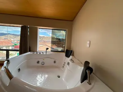 a large white bath tub in a bathroom with windows at Duplex panorámico in Cusco
