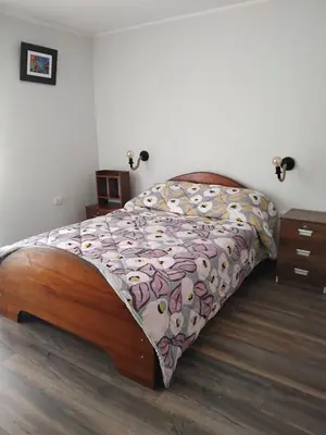 a bedroom with a large bed with a wooden frame at La Casa de Anni Departamento 3 in Oxapampa