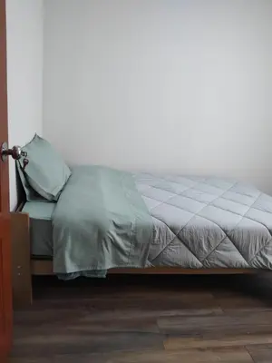 a bed in a room with a white wall at La Casa de Anni Departamento 3 in Oxapampa